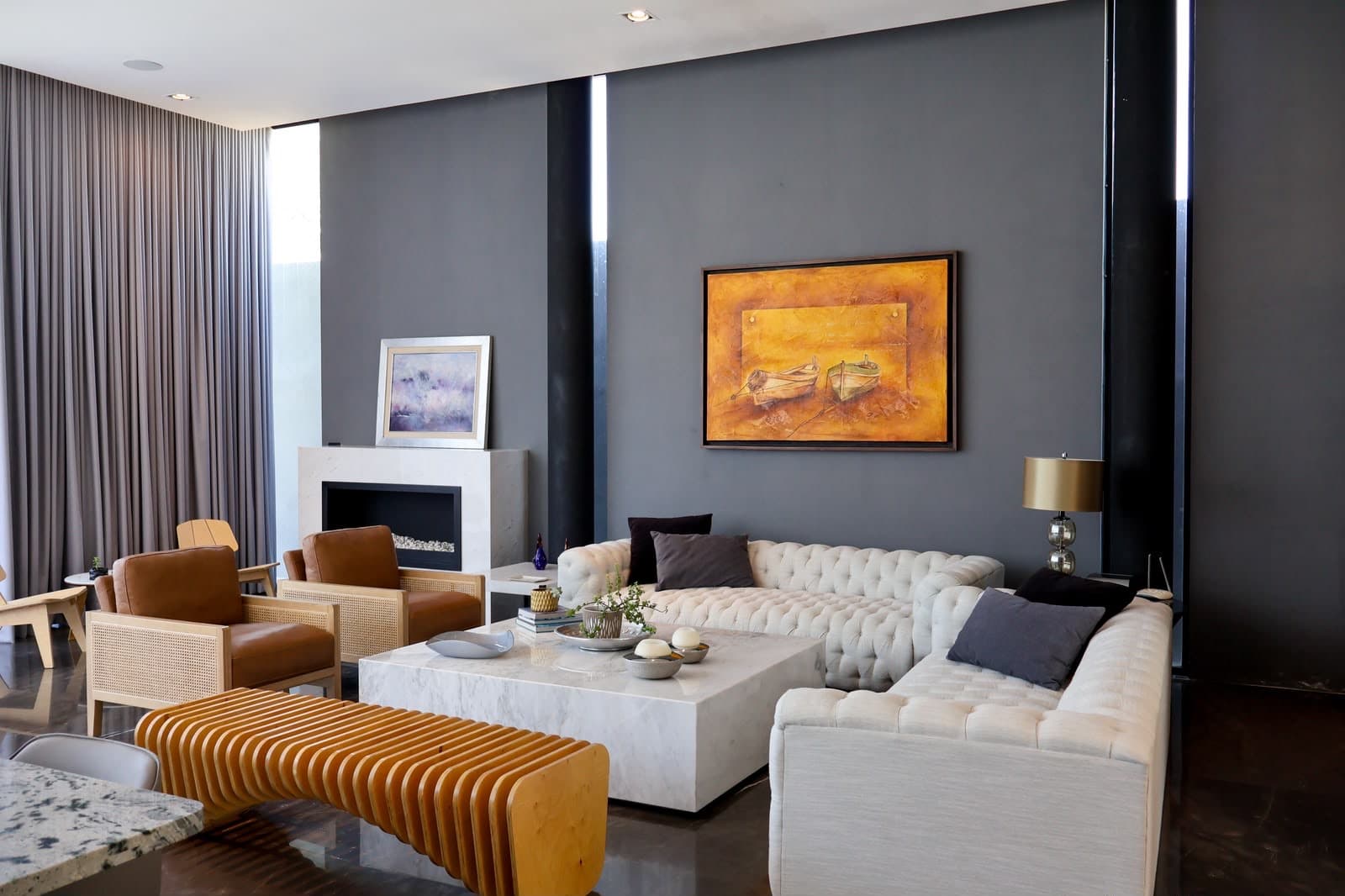 The Gardenia living room — charcoal plaster, tufted linen, and a marble block table beneath a bronze-framed canvas